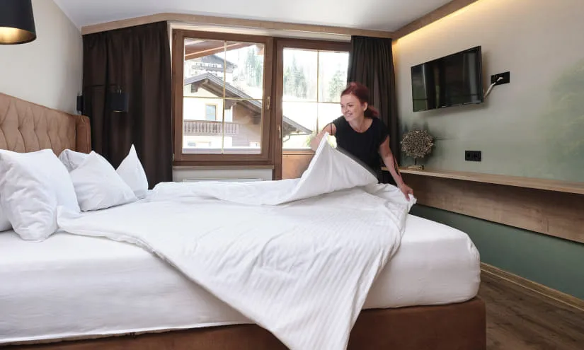 Zimmermädchen beim Bettenmachen in einem Hotelzimmer