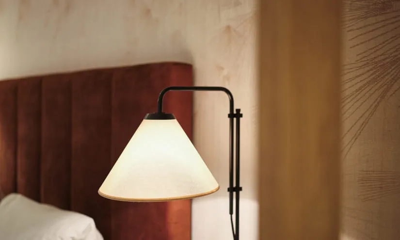 Nachttischlampe neben einem Bett mit rotem Kopfteil